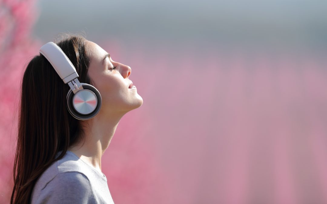 Woman meditating listening audio on headphones in a field