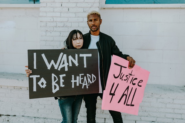 two people holding signs for justice