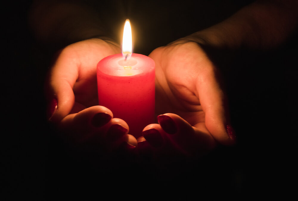 A lighted candle cradled in hands