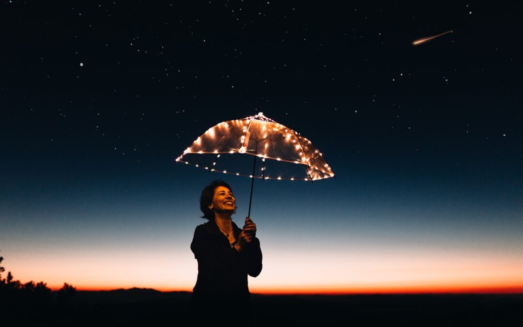 Woman standing under a clear umbrella at night with lights on it