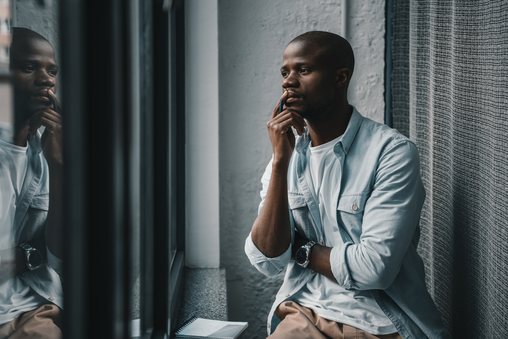 African American man looking sadly out the window